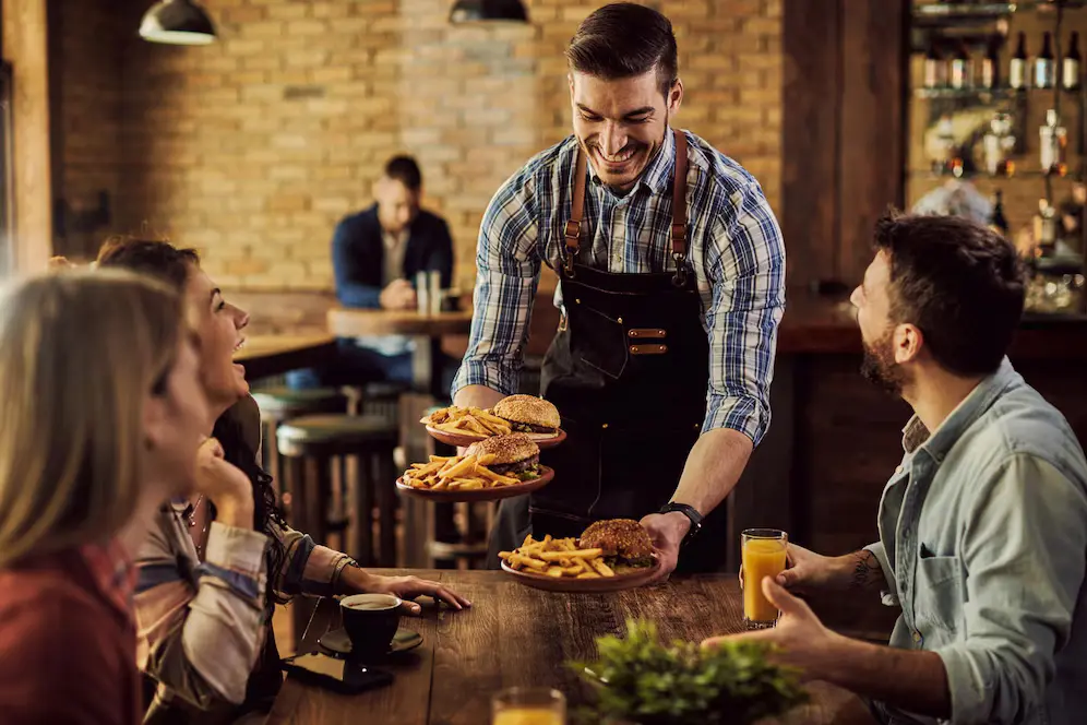 A happy busboy serving food, implying the importance of employee advocacy in public relations for restaurants