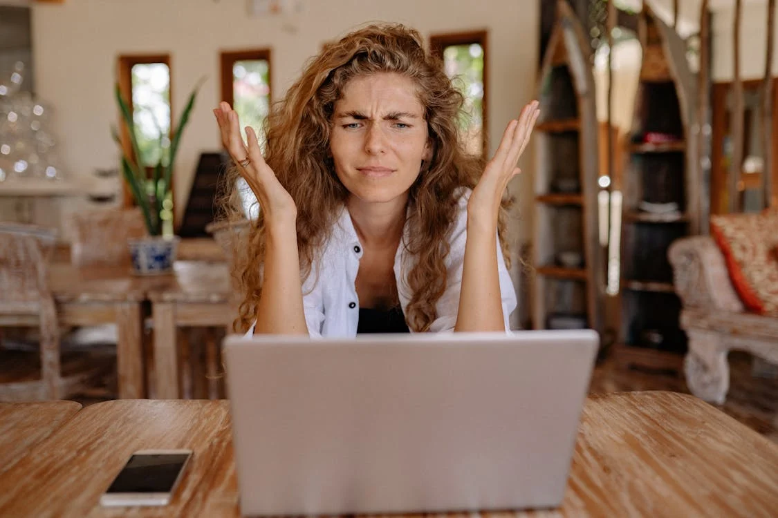 A distressed woman in front of her laptop wondering how to respond to negative restaurant reviews