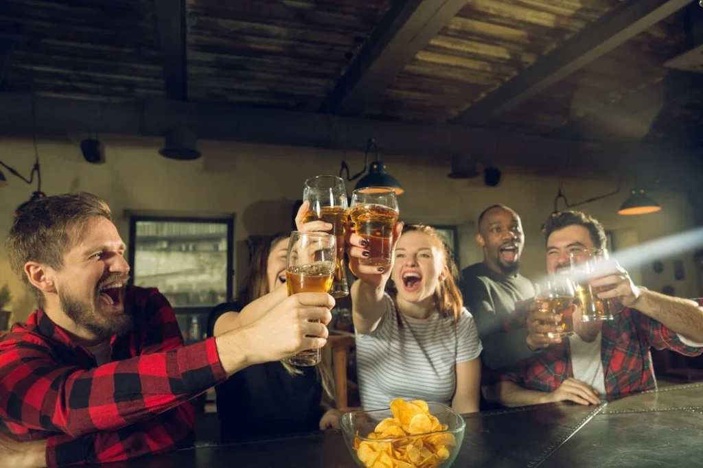 Lively sports bar scene shows why atmosphere is important in a restaurant friends cheering, toasting drinks, enjoying snacks