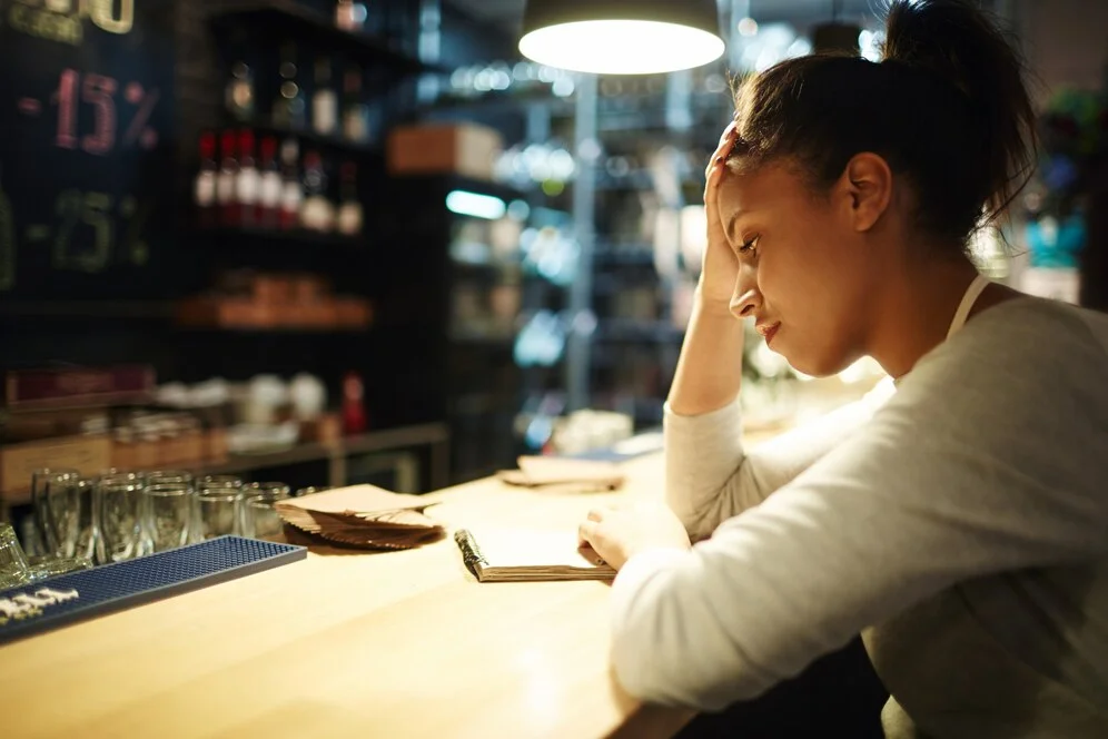 A restaurant owner looks stressed at the bar counter, wondering why do most restaurants fail.